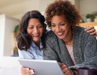 two-women-smiling-holding-tablet